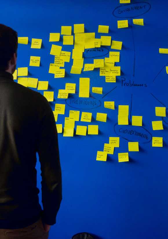 Man looking at blue wall with sticky notes